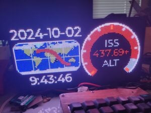 Photo of an LED matrix display showing the date, time, a map of the space station's path, and a dial showing the space station's altitude